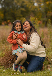 mom and daughter sitting on moms lap laughing during fall in cleveland ohio