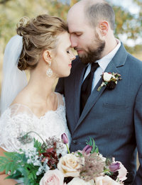 Bride and groom embrace in loving moment forehead to forehead