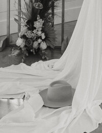 Gigi Pip hat rests on the train of a brides wedding dress
