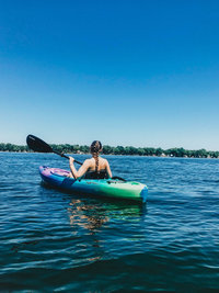 woman in kayak paddling across lake