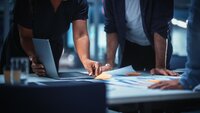 people pointing to paper on a desk