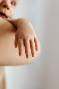 Close-up of a newborn’s delicate hand resting on parent’s arm – captured during a natural light in-home newborn photography session in Las Vegas by Angela Wolf Photography