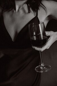 black and white picture of a woman holding a red wine glass