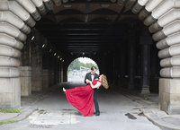 husband dips wife in red dress under a bridge in Paris