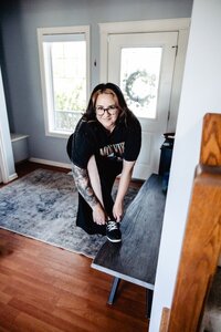 a woman in her entryway leans over to tie her shoe