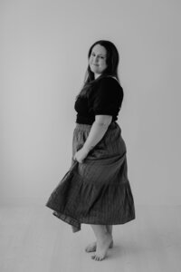 Black and white photo of Bethany Simms, photographer, spinning in dress and looking at camera