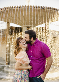 A person kissing their partner's cheek as they smile 