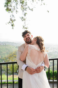 groom laughs when  bride kisses his neck