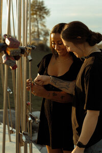 Smiling couple attaching a love lock together at Chambers Bay during golden hour