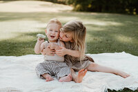 Sweet moment of siblings exploring nature and sharing a flower during their family photography session in a sunlit field near Charlotte, NC.