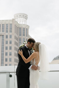Bride and groom sharing an intimate moment on a rooftop at Dr. Phillips Center for the Performing Arts in Orlando, Florida — modern wedding portrait with cityscape backdrop and romantic embrace.