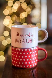 Close up of red and white coffee mugs with quote saying "All You Need is Love and Coffee"