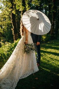 Bride and groom sharing a kiss behind a parasol, their shadows visible in the golden light, captured by a Washington wedding photographer.