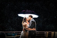 Couple kissing under umbrella during rain