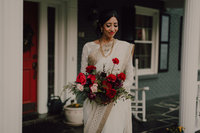Beautiful Indian bride holds stunning red bouquet