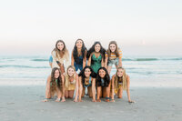 Free-spirited senior portrait photograph with the model team girls of Nicole Marie Photography. They are joyfully running down the beach in Ocean City. The ferris wheel is behind them.