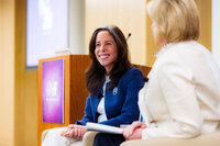 A woman smiling while sitting on a panel at a conference