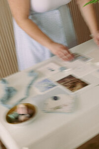 A blurry image of a wedding planner creating a flat lay of a wedding invitation suite with additional decorations