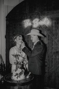 groom puts frosting on brides nose as they but their wedding cake