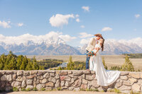 Bride and groom sharing a romantic dip kiss at the breathtaking Snake River Overlook in Jackson, Wyoming, with the stunning Teton Range as the perfect backdrop for their unforgettable wedding day.