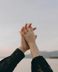 couple holding hands with water in the background