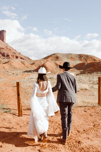 Bride and groom walking away with desert views in Moab