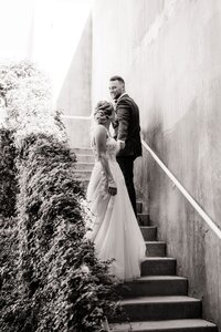 Groom walking past bride on the stairs touching hands.