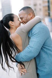 Candid moment of a couple embracing and laughing during an engagement shoot in an urban city environment