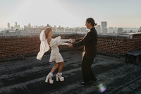 A couple on a roof top celebrating an engagement dancing together 
