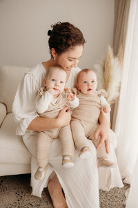 A mother holding her two little babies during their family photoshoot with auckland photographer michelle kelly