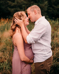 Maternity Photographer, Pregnant woman being held be her husband outside