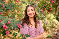 Charlotte Area graduate stands in a floral dress surrounded by a blooming tree during her senior photography session