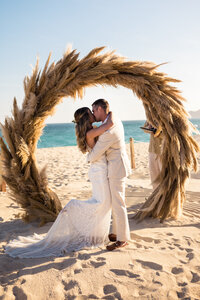 Bride and groom kissing on beach 
