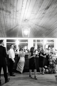 Black and White photo of a bar at a wedding with guests standing around