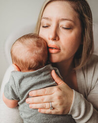 Newborn Photographer, a mother holds onto her newborn baby