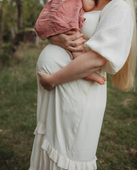 A woman embracing her pregnant belly and holding her other child in Blacksburg, Virginia.