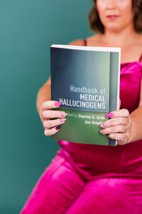 Ketamine-assisted psychotherapy practitioner holding the book, "Handbook of Medical Hallucinations" in Canon City