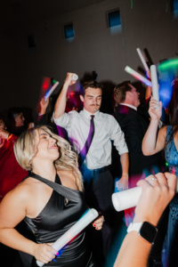 Crowd of people with glow wands dancing reception