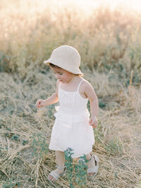 Little girl wearing white walking through grass