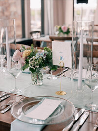 Wedding table number in gold stand surrounded by pastel flowers.