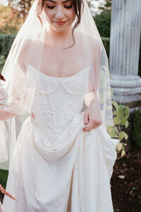 A bride with a heavily detailed gown wearing a delicate veil with pearls