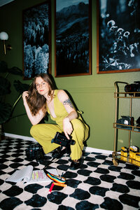 woman kneels on floor with camera equipment