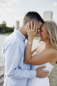 A photo of a couple with their foreheads together smiling for a picture 