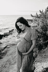 beautiful pregnant woman poses with belly at the beach in black and white