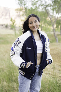 A high school senior posing in her letterman's jacket for her senior portraits.