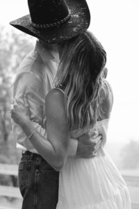 Black and white image of woman kissing man in a cowboy hat during Nashville engagement photos