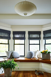 Interior designers in Boston created a modern look in a historic Brookline home entry with a window seat and brown leather cushions accented by a mid-century modern light.