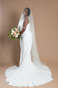 Bride wearing a long veil with blusher and holding a bouquet