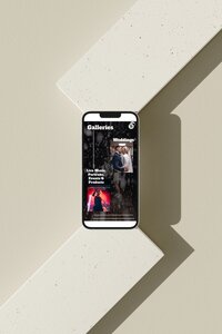 A smartphone displaying the galleries section of a wedding photographer's website. The screen shows two main categories: "Weddings," featuring a photo of a bride and groom, and "Live Music, Portraits, Events & Products," featuring a photo of a performer on stage. The phone is set against a light-coloured geometric surface with shadows creating a modern and minimalist aesthetic.