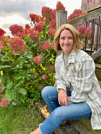 Jess sitting on her front steps in front of blooming red flowers